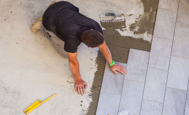 A man working on tile installation on a floor, part of a tile flooring service in Springfield, IL.