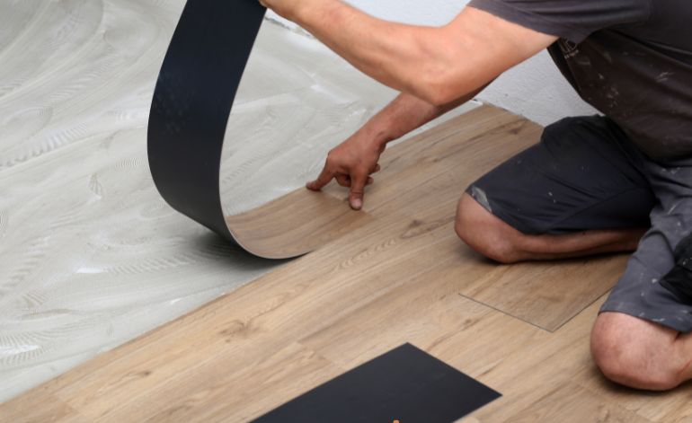 A man is installing a piece of luxury vinyl flooring in Springfield, IL, showcasing a flooring service in action.
