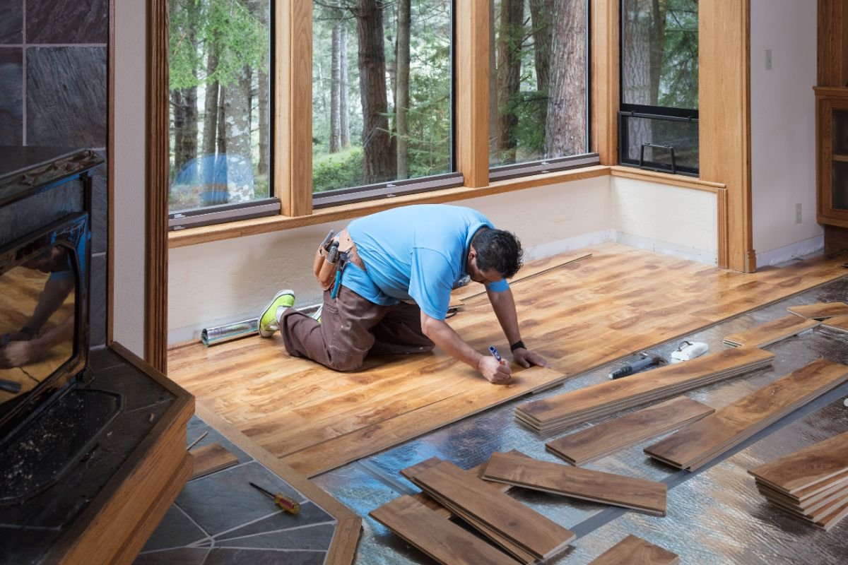 A man installs wood flooring in a room, showcasing professional flooring service in action.