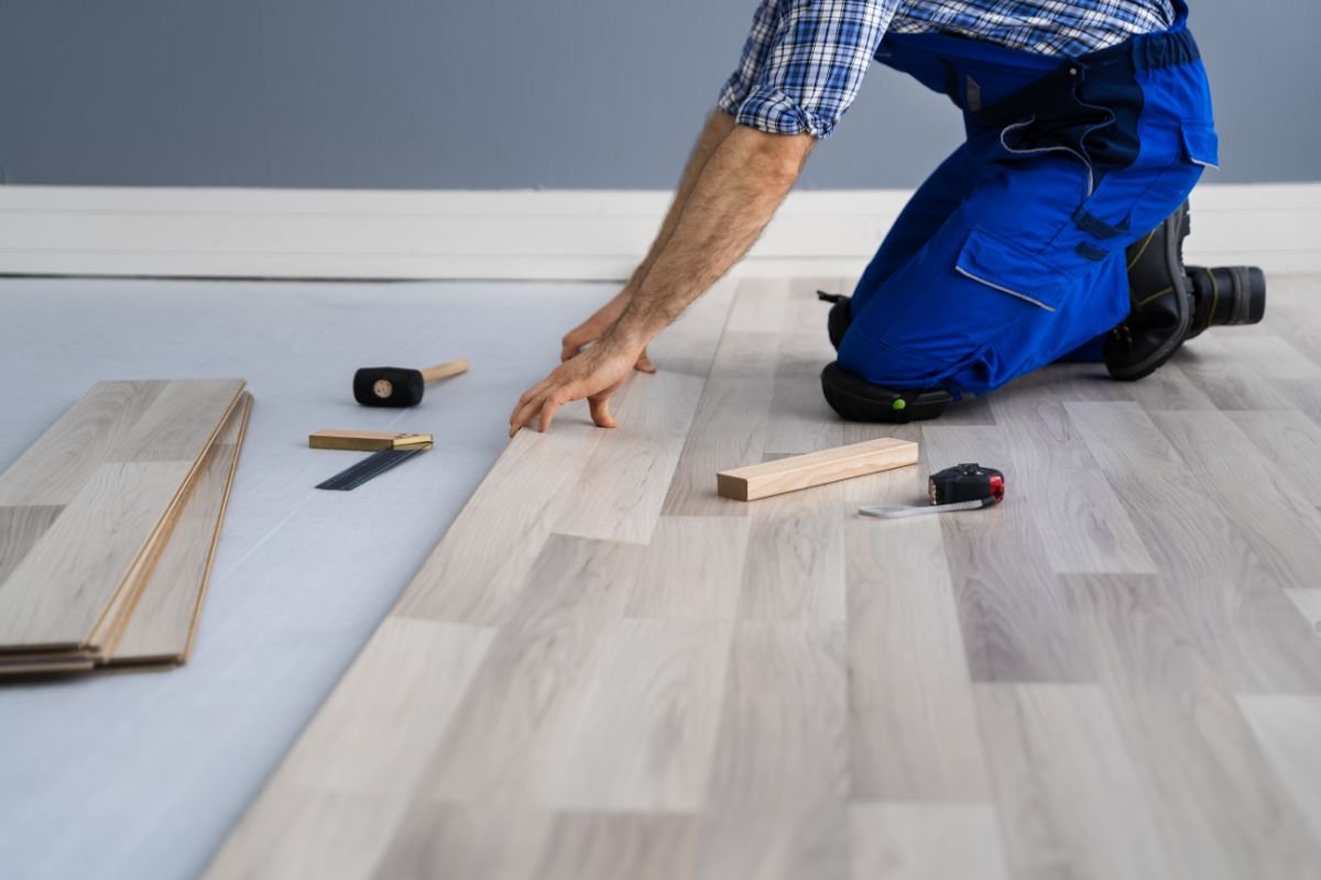 A man installing wood flooring, demonstrating professional flooring service in a well-lit interior space.