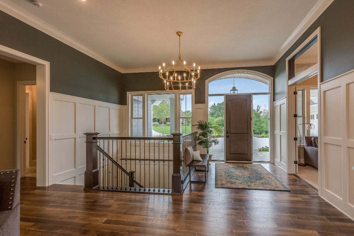 A foyer featuring elegant hardwood floors and a stunning chandelier, showcasing quality flooring service.